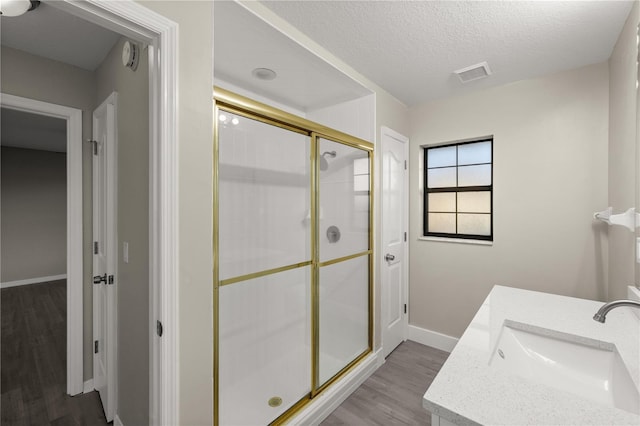 bathroom featuring a textured ceiling, hardwood / wood-style floors, vanity, and an enclosed shower