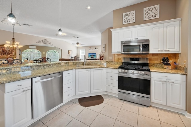 kitchen featuring sink, light stone counters, hanging light fixtures, appliances with stainless steel finishes, and white cabinets