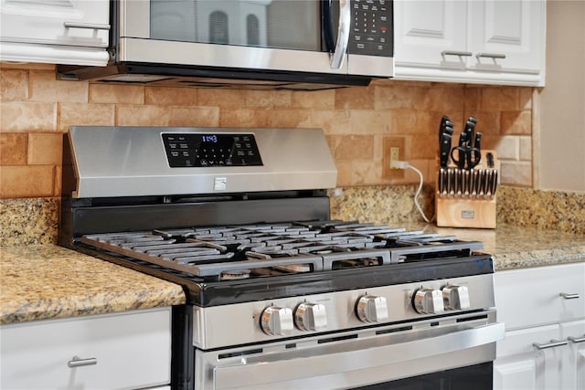 kitchen with white cabinetry, backsplash, light stone counters, and appliances with stainless steel finishes