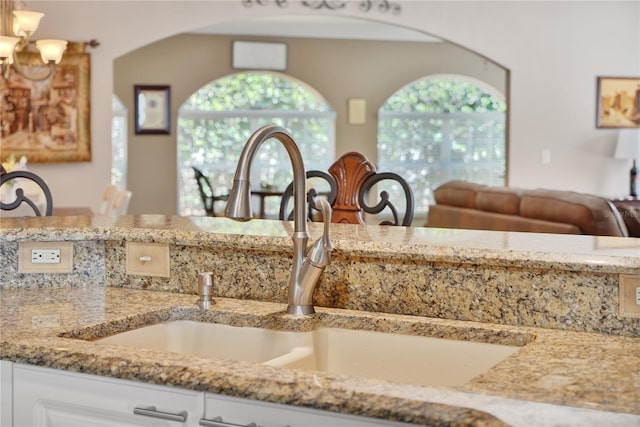 interior space featuring light stone counters, sink, and white cabinets