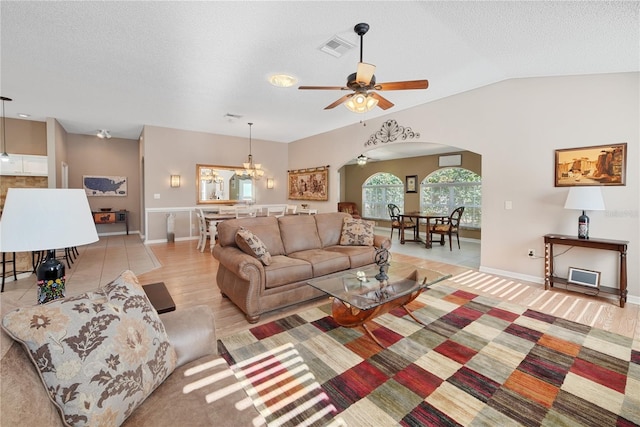 living room featuring lofted ceiling, ceiling fan with notable chandelier, a textured ceiling, and light wood-type flooring