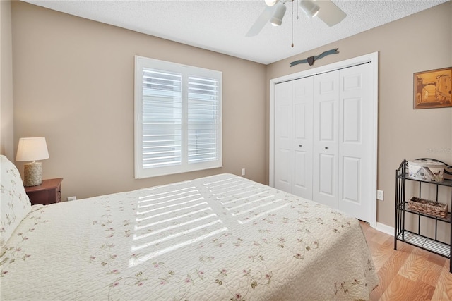 bedroom with ceiling fan, a textured ceiling, light hardwood / wood-style floors, and a closet