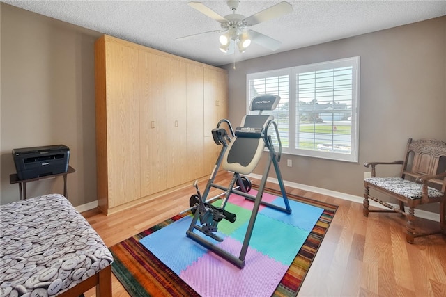 workout area featuring ceiling fan, a textured ceiling, and light wood-type flooring