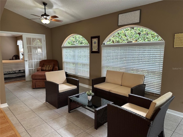 tiled living room featuring ceiling fan, lofted ceiling, and a textured ceiling