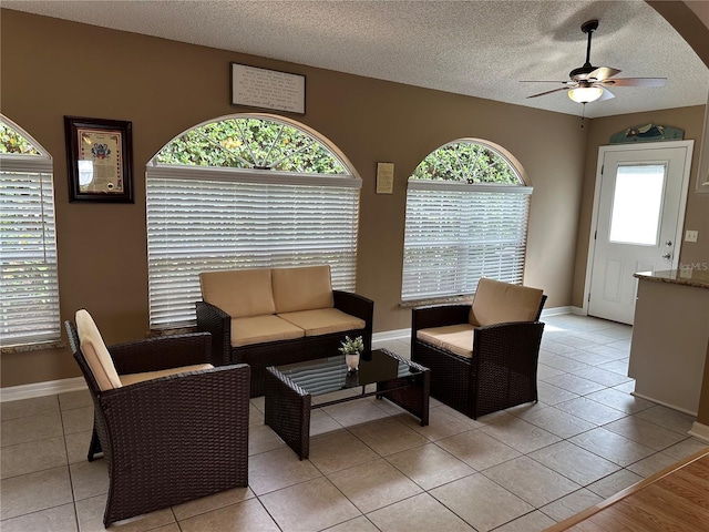 tiled living room with ceiling fan and a textured ceiling