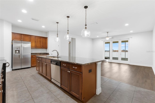 kitchen with stainless steel appliances, a kitchen island with sink, ceiling fan, sink, and hanging light fixtures