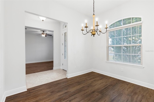 tiled empty room featuring ceiling fan with notable chandelier