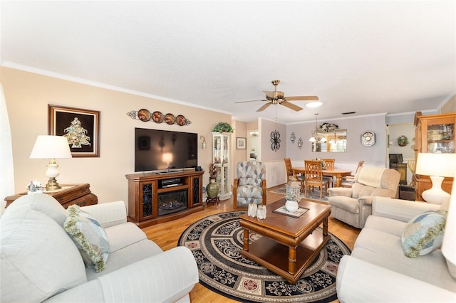 living room featuring ceiling fan, light hardwood / wood-style floors, and ornamental molding