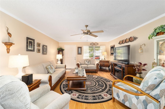 living room with a textured ceiling, hardwood / wood-style flooring, ceiling fan, and crown molding