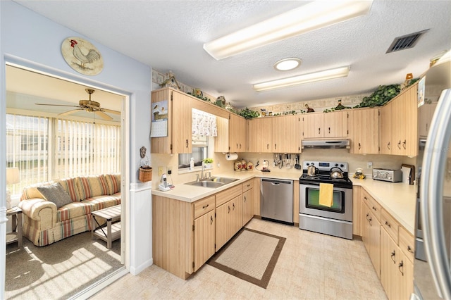 kitchen with light brown cabinetry, a textured ceiling, and appliances with stainless steel finishes