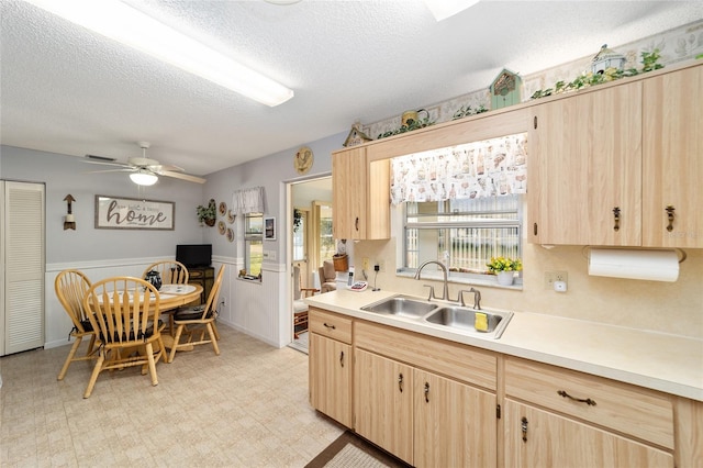 kitchen featuring light brown cabinetry, ceiling fan, sink, and a textured ceiling