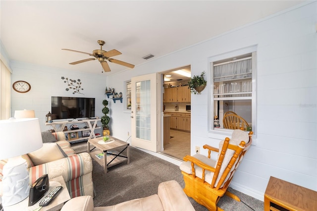 living room with ceiling fan, carpet floors, and ornamental molding