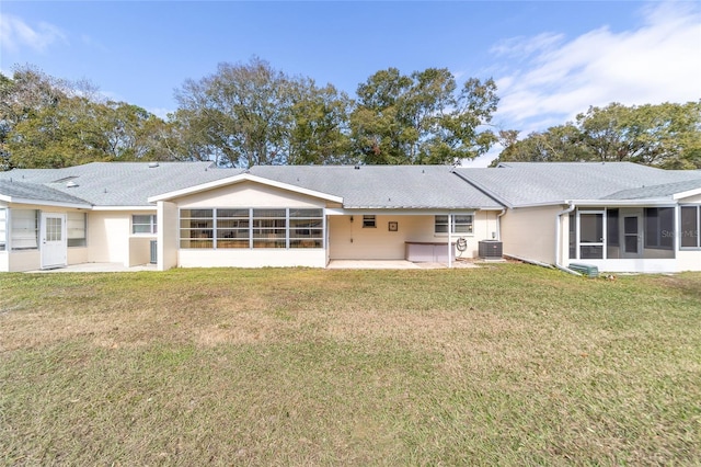 back of property with a sunroom, central air condition unit, a patio, and a yard