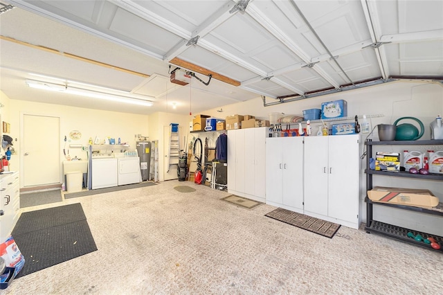 garage featuring electric water heater, sink, washer and dryer, and a garage door opener