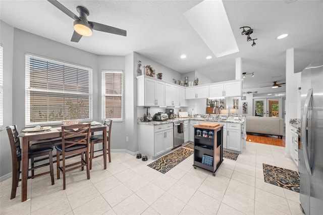 kitchen featuring white cabinets, a healthy amount of sunlight, light tile patterned floors, and appliances with stainless steel finishes