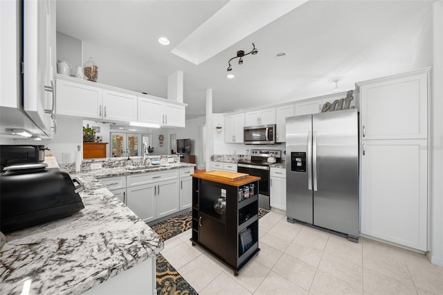 kitchen with kitchen peninsula, stainless steel appliances, sink, light tile patterned floors, and white cabinets