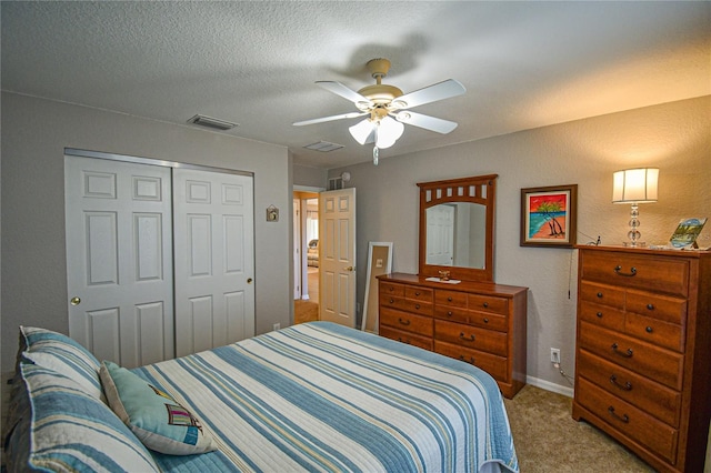 carpeted bedroom featuring ceiling fan, a textured ceiling, and a closet