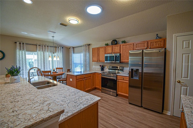 kitchen featuring pendant lighting, lofted ceiling, sink, kitchen peninsula, and stainless steel appliances