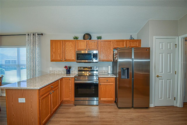 kitchen featuring light stone countertops, light wood-type flooring, kitchen peninsula, and stainless steel appliances