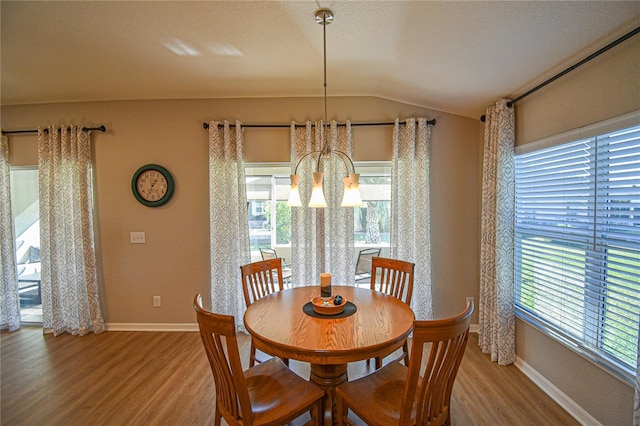 dining area with a chandelier, wood-type flooring, lofted ceiling, and a healthy amount of sunlight