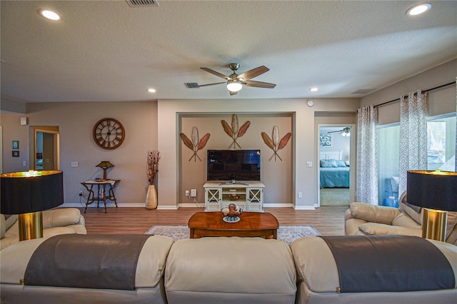 living room featuring a textured ceiling, light hardwood / wood-style flooring, and ceiling fan