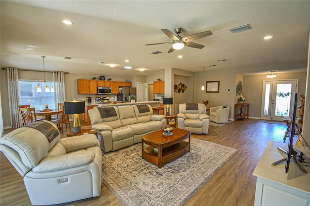 living room with a textured ceiling, ceiling fan, and dark wood-type flooring