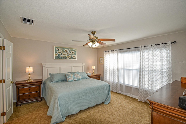 bedroom with ceiling fan, light carpet, and a textured ceiling