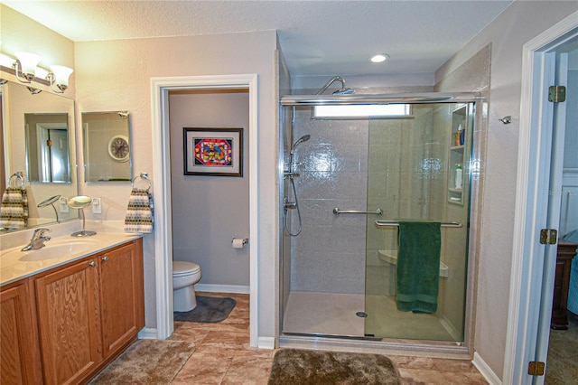 bathroom featuring a shower with door, vanity, and toilet