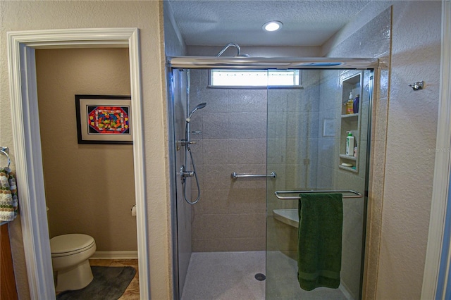 bathroom with toilet, a shower with door, and a textured ceiling