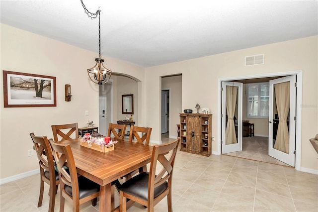 dining space featuring french doors, light tile patterned floors, and a chandelier