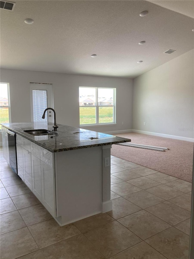 kitchen with white cabinets, stainless steel dishwasher, a kitchen island with sink, and a healthy amount of sunlight