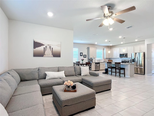 tiled living room featuring ceiling fan and sink