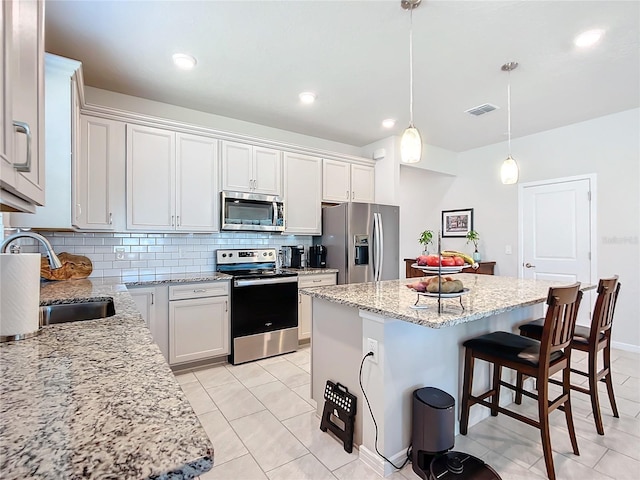 kitchen featuring stainless steel appliances, sink, pendant lighting, white cabinetry, and a kitchen island