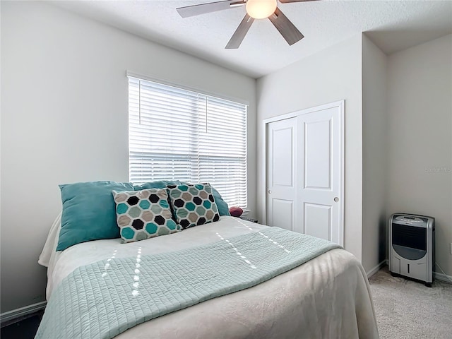 bedroom featuring carpet, heating unit, ceiling fan, multiple windows, and a closet