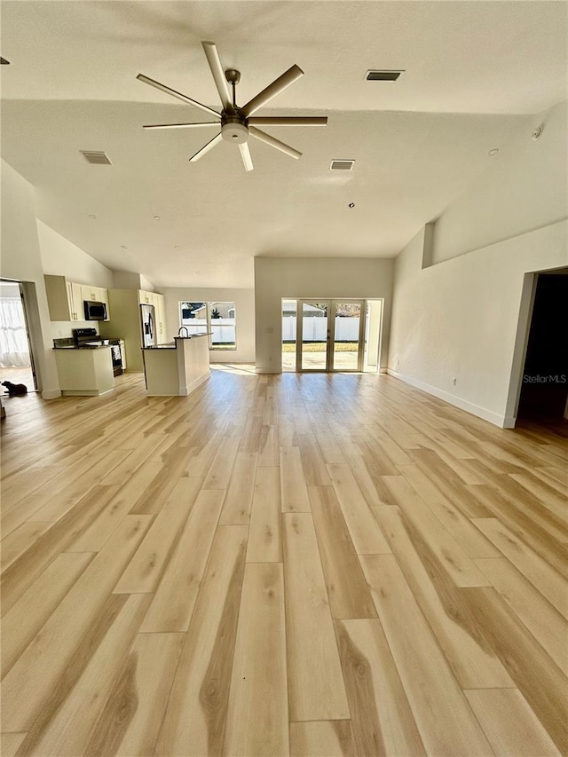 unfurnished living room featuring vaulted ceiling, ceiling fan, light hardwood / wood-style floors, and french doors