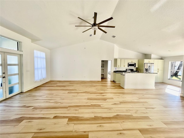 unfurnished living room featuring french doors, lofted ceiling, ceiling fan, and light hardwood / wood-style flooring