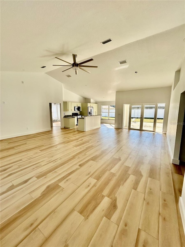 unfurnished living room with vaulted ceiling, ceiling fan, and light wood-type flooring