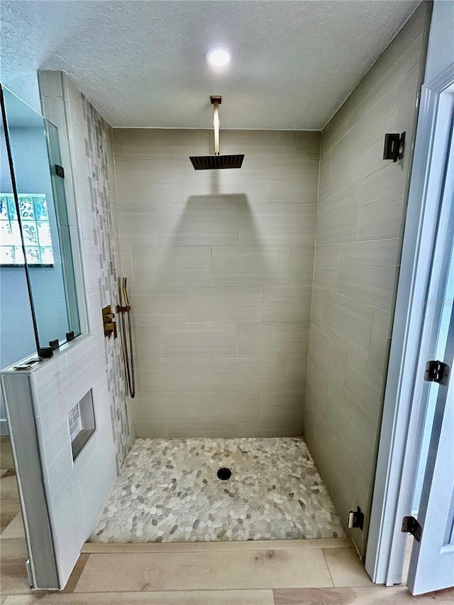 bathroom with a textured ceiling and tiled shower