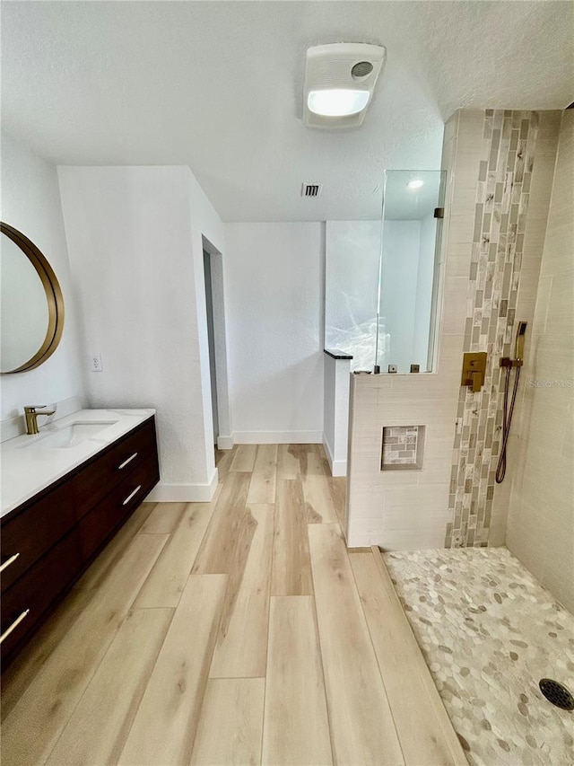 bathroom featuring a tile shower, vanity, hardwood / wood-style flooring, and a textured ceiling