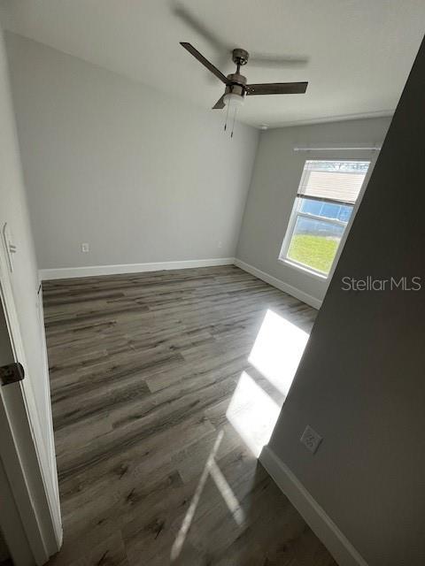 empty room with ceiling fan, baseboards, and wood finished floors