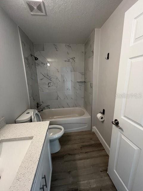 full bathroom with a textured ceiling, toilet, wood finished floors, vanity, and visible vents