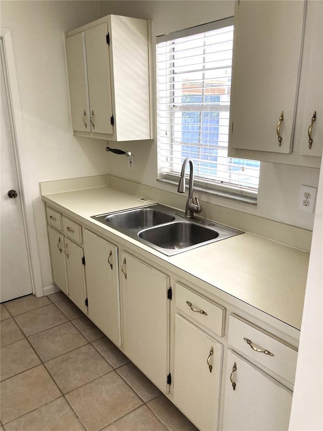 kitchen with white cabinetry, sink, and light tile patterned flooring