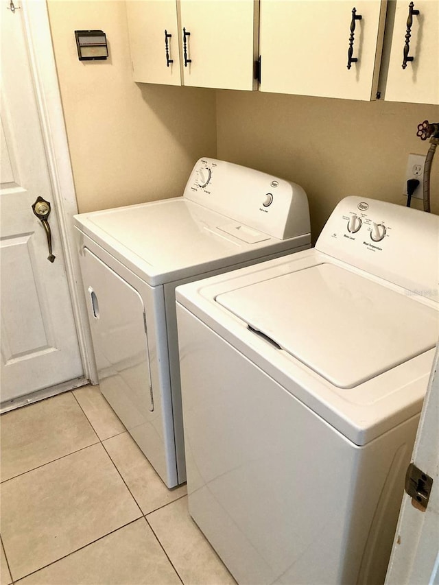 laundry room featuring washer and dryer, light tile patterned floors, and cabinets