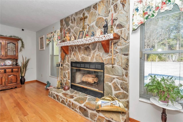 details featuring hardwood / wood-style flooring, a stone fireplace, and a textured ceiling