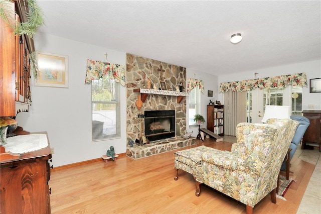 living room featuring hardwood / wood-style floors, a textured ceiling, and a stone fireplace