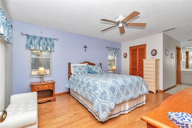 bedroom with ensuite bathroom, a textured ceiling, ceiling fan, hardwood / wood-style flooring, and a closet