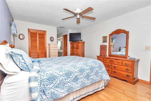 bedroom with ceiling fan, light wood-type flooring, a textured ceiling, and a closet