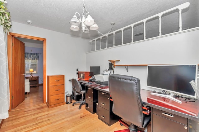 home office with a textured ceiling, light hardwood / wood-style floors, and an inviting chandelier