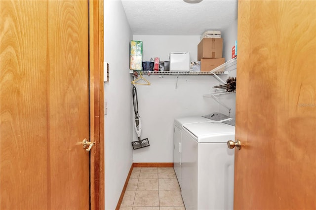 laundry room with light tile patterned floors, washer and dryer, and a textured ceiling