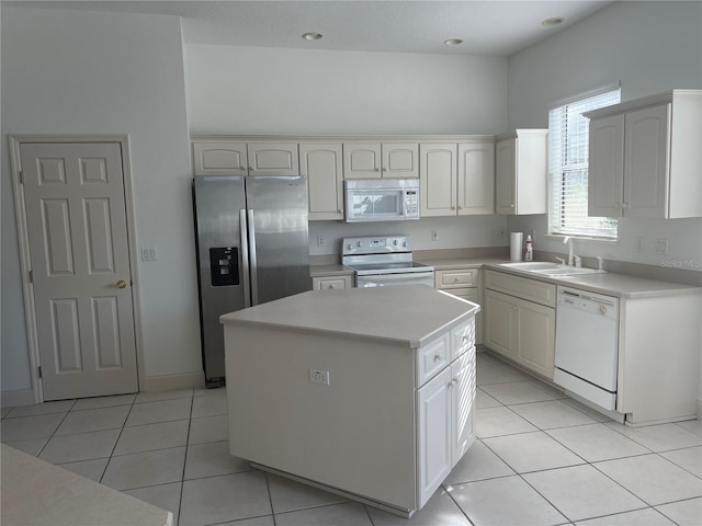 kitchen featuring white appliances, light tile patterned flooring, a sink, light countertops, and a center island